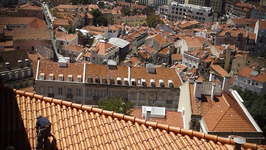 A painter works on the roof of a house Monday, Aug. 8, 2011, on a slope above Lisbon's Mouraria neigborhood, one of the city's oldest quarters. (AP Photo/Francisco Seco)